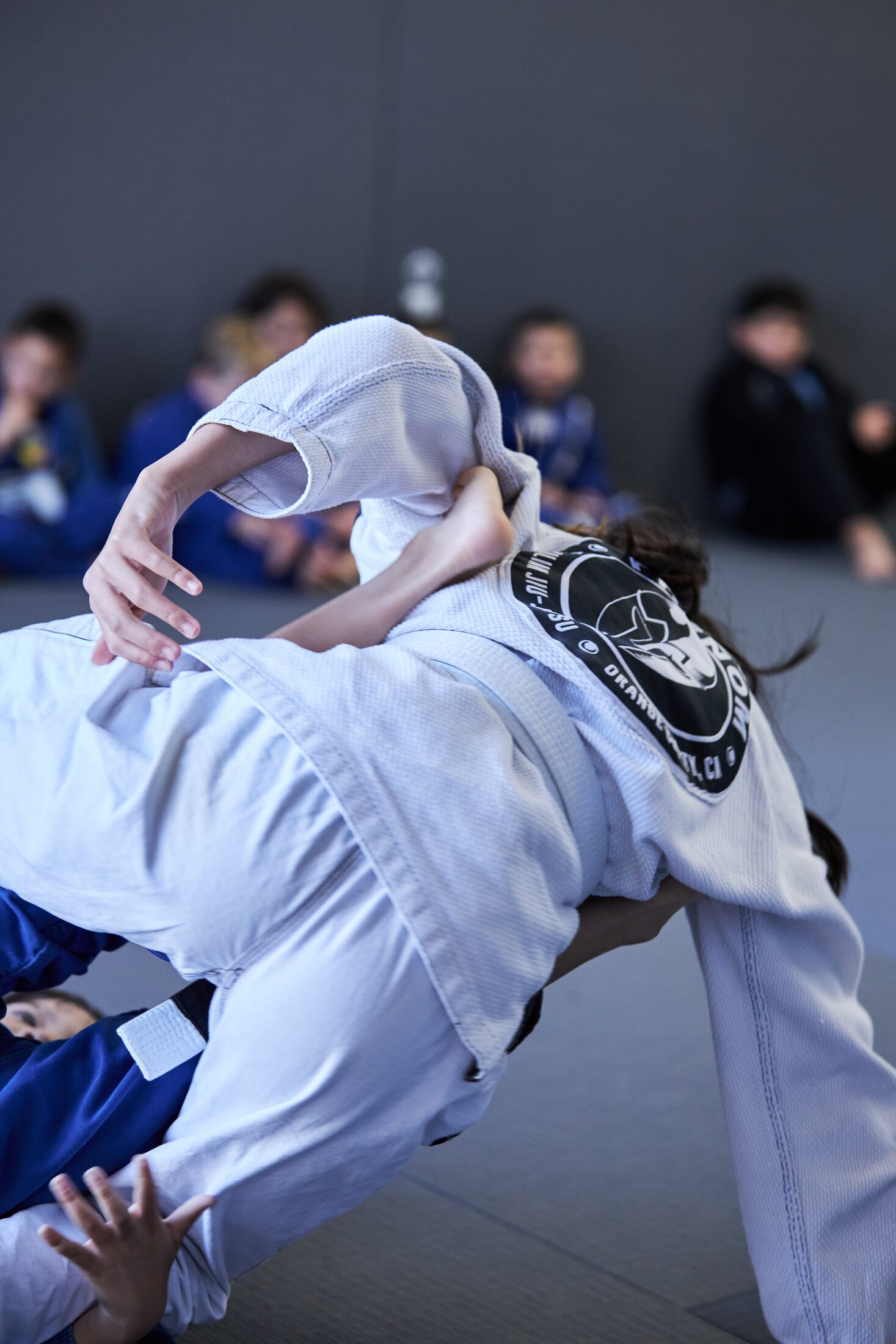Young student executing a sweep during a kids Brazilian Jiu-Jitsu class in Irvine