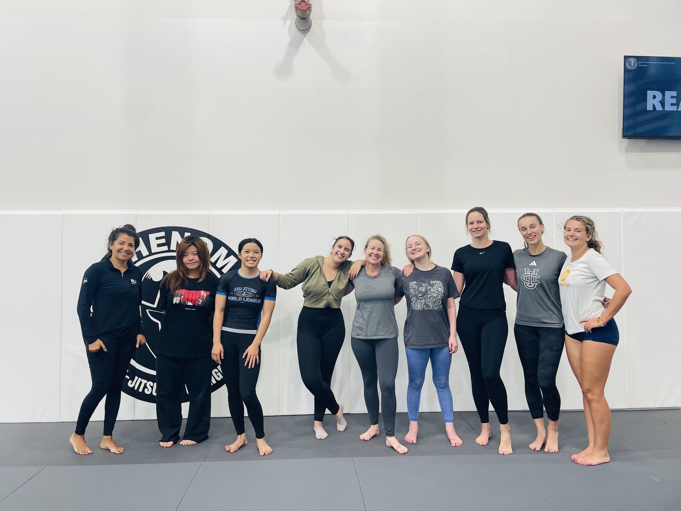 Women's beginner Brazilian Jiu-Jitsu class lined up together on the mats after training at Phenom BJJ Irvine